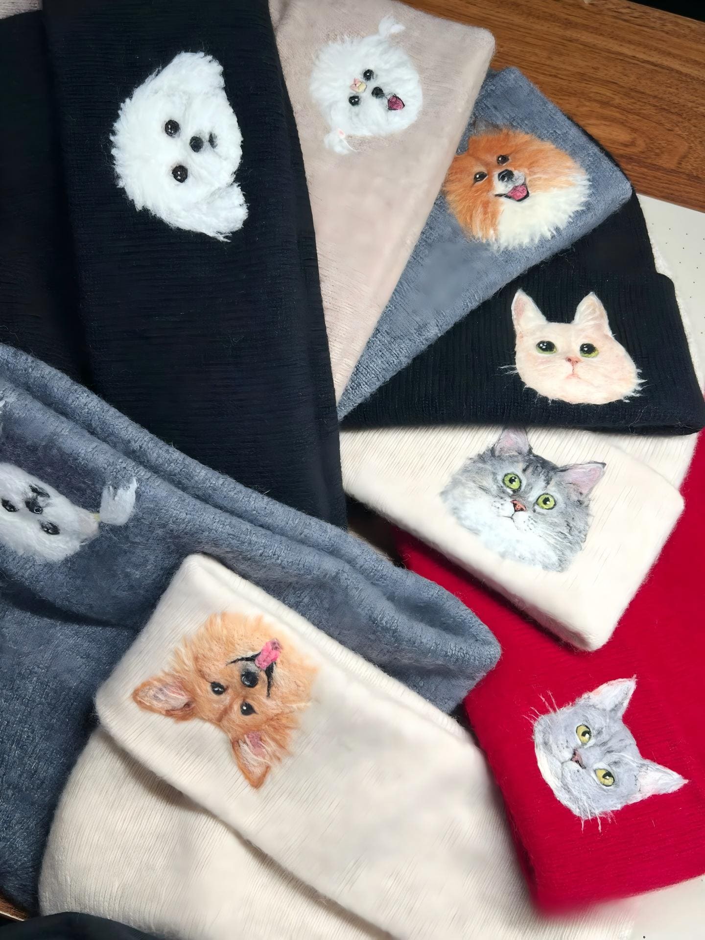 Assorted cat-applique knit beanies in black, grey, white, and red—flat lay