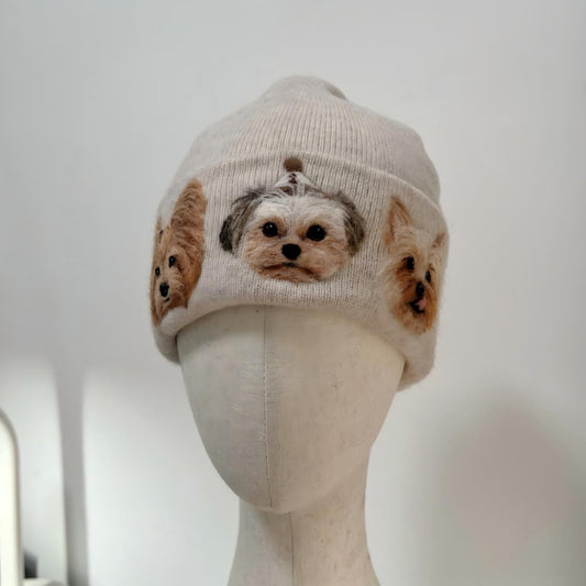 Beige knit beanie hat with three animal face patches and ribbed cuff.