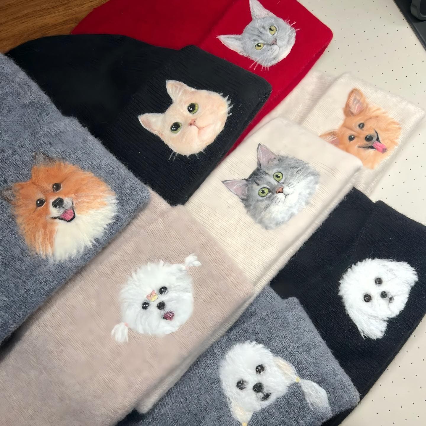 Cat-applique knit beanies in black, cream, and pink with stitched animal faces