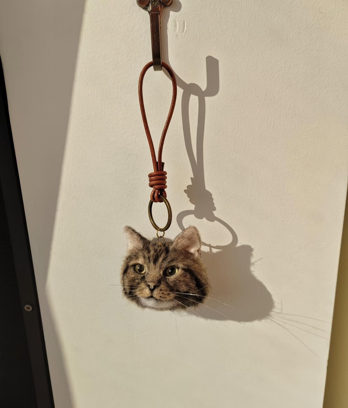 Cat face keychain with brown cord and metal ring attachment