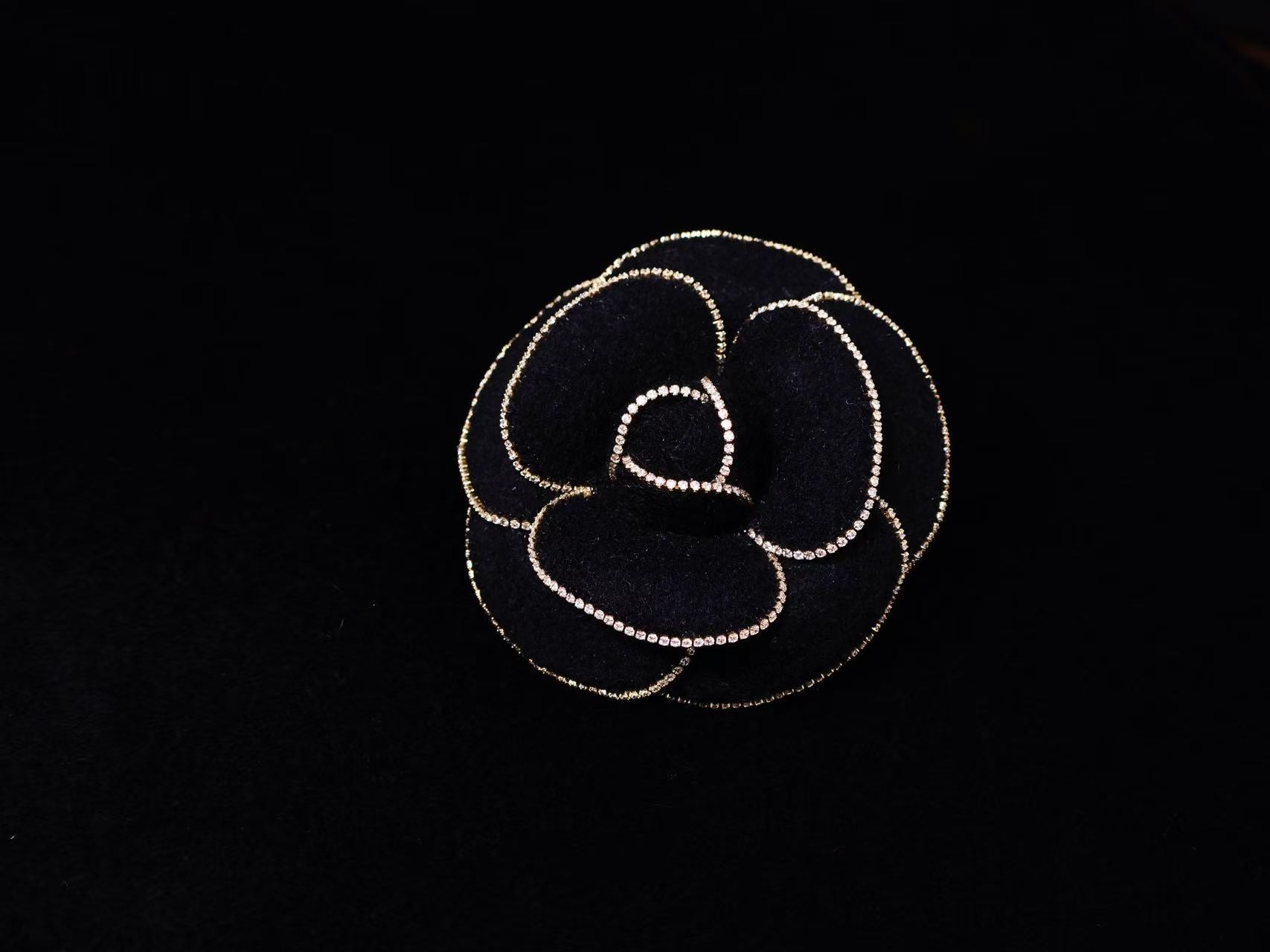 Black camellia brooch with gold beaded outline and heart-shaped center
