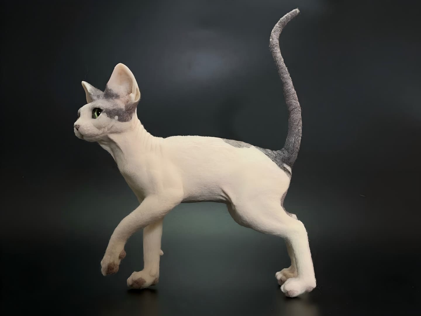 White cat figurine in profile, tail raised and green eyes, full-body stance