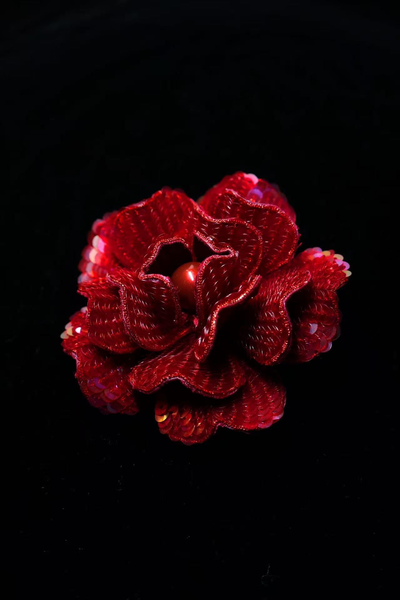 Red camellia brooch with sequined petals and a small dark bead center