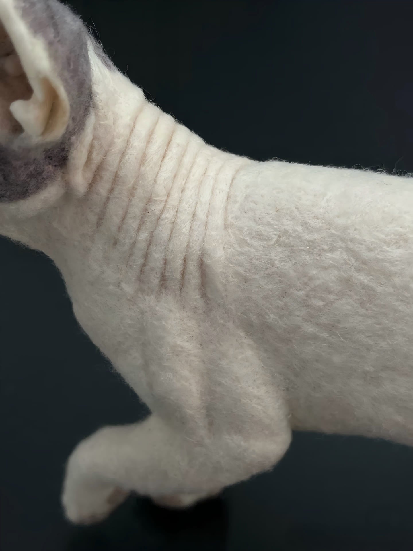 White cat figurine close-up of tail and hind leg in soft fur texture